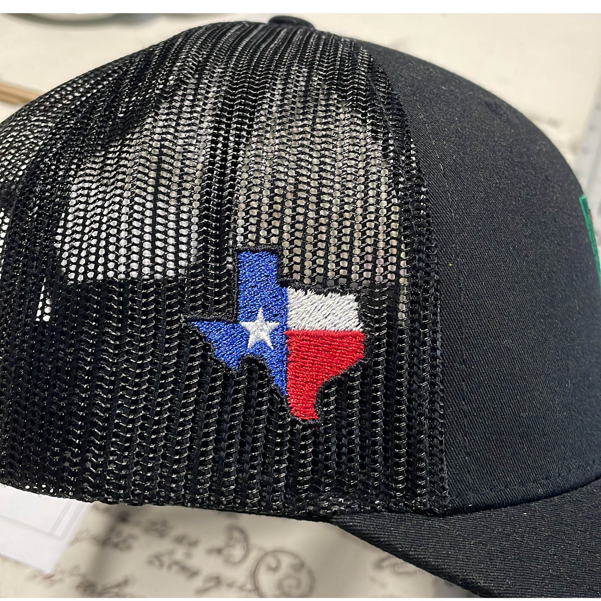 Black mesh cap with a small Texas flag emblem on the front.