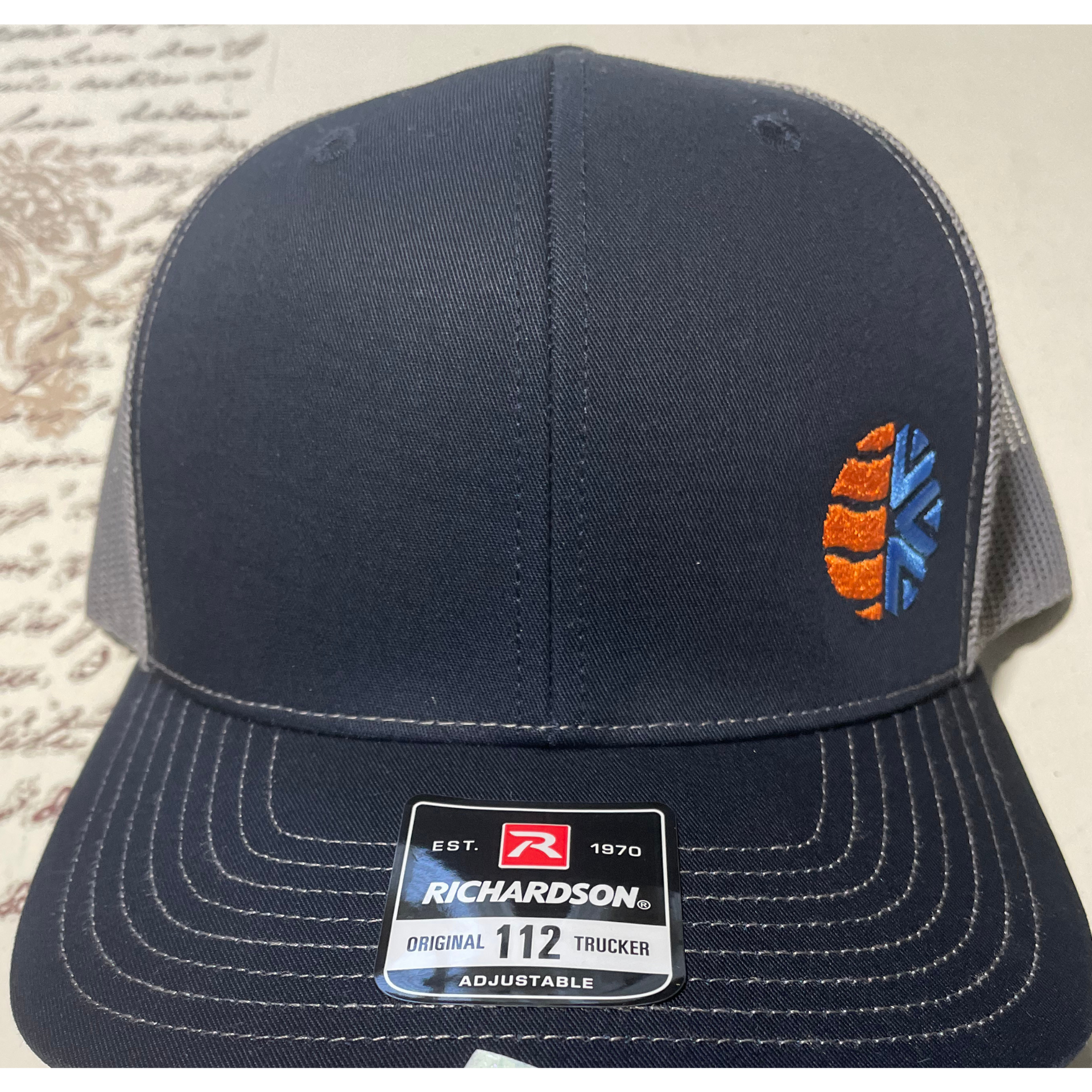Navy blue Richardson baseball cap with an orange-and-blue embroidered logo on the side
