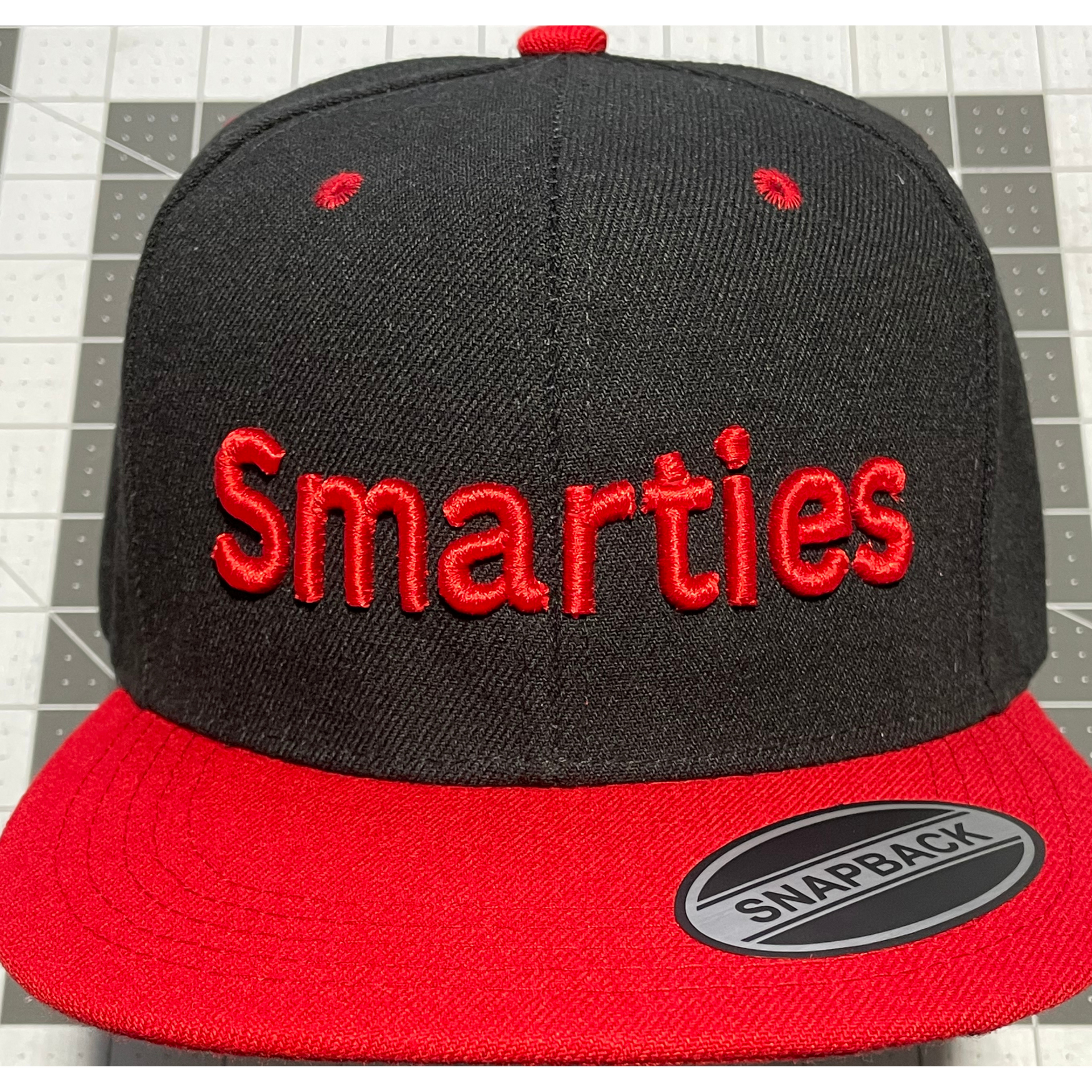 Black and red Smarties Snapback cap with red embroidered logo on the front