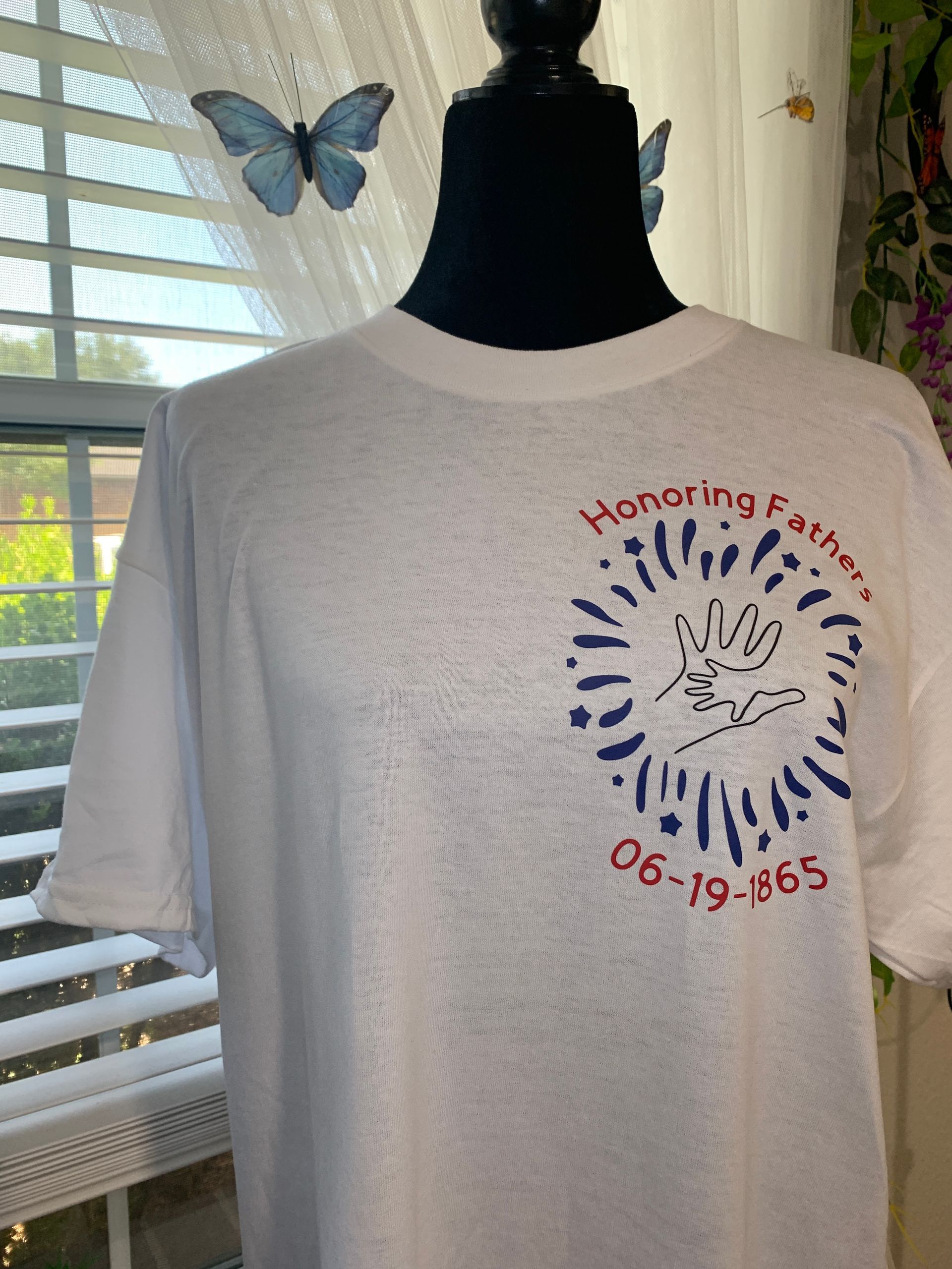 White T-shirt on a mannequin with a commemorative breast cancer awareness print and butterfly design near a window