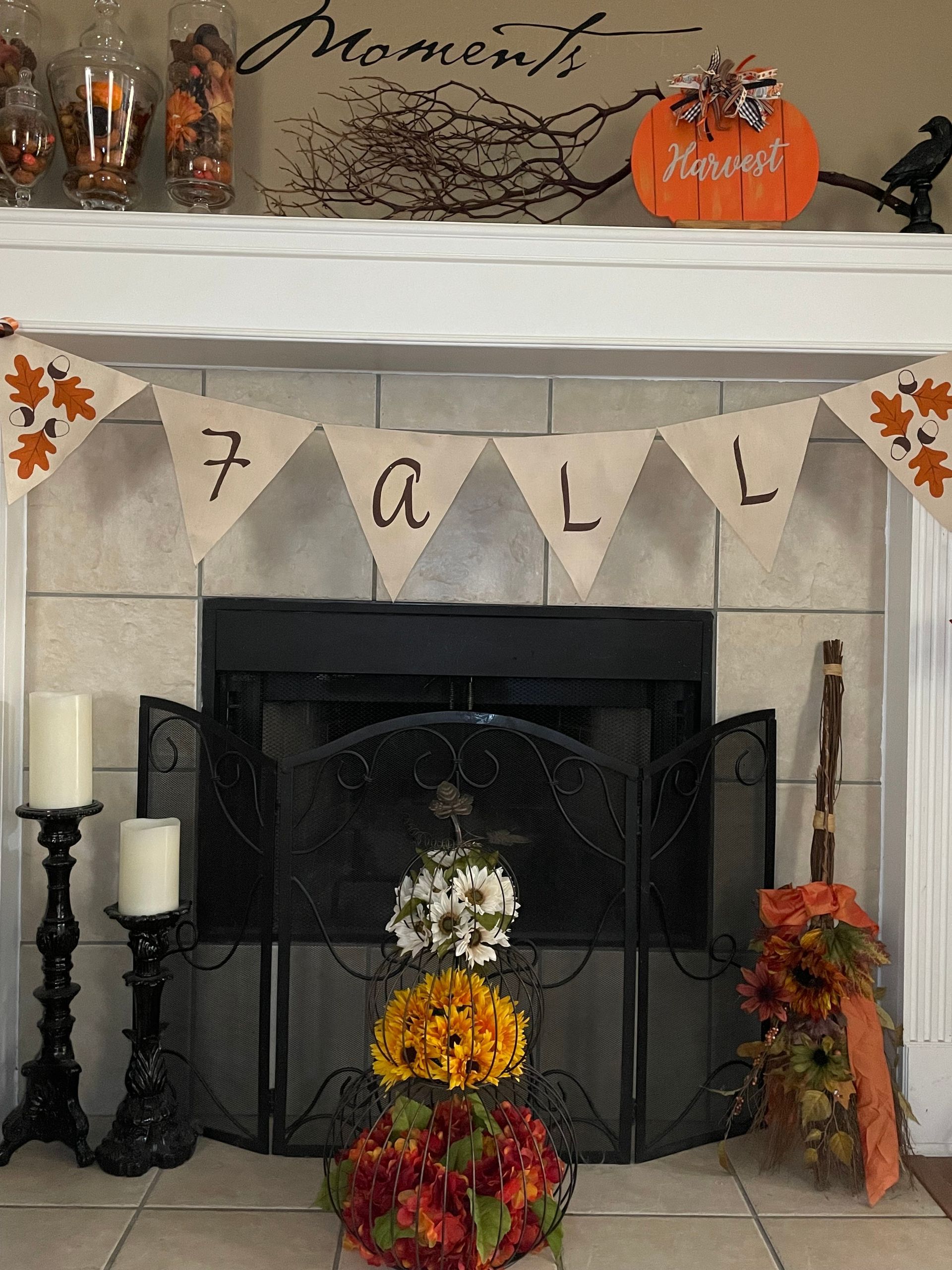 Fall fireplace mantel with pumpkins, autumn garland, and a banner reading “FALL”