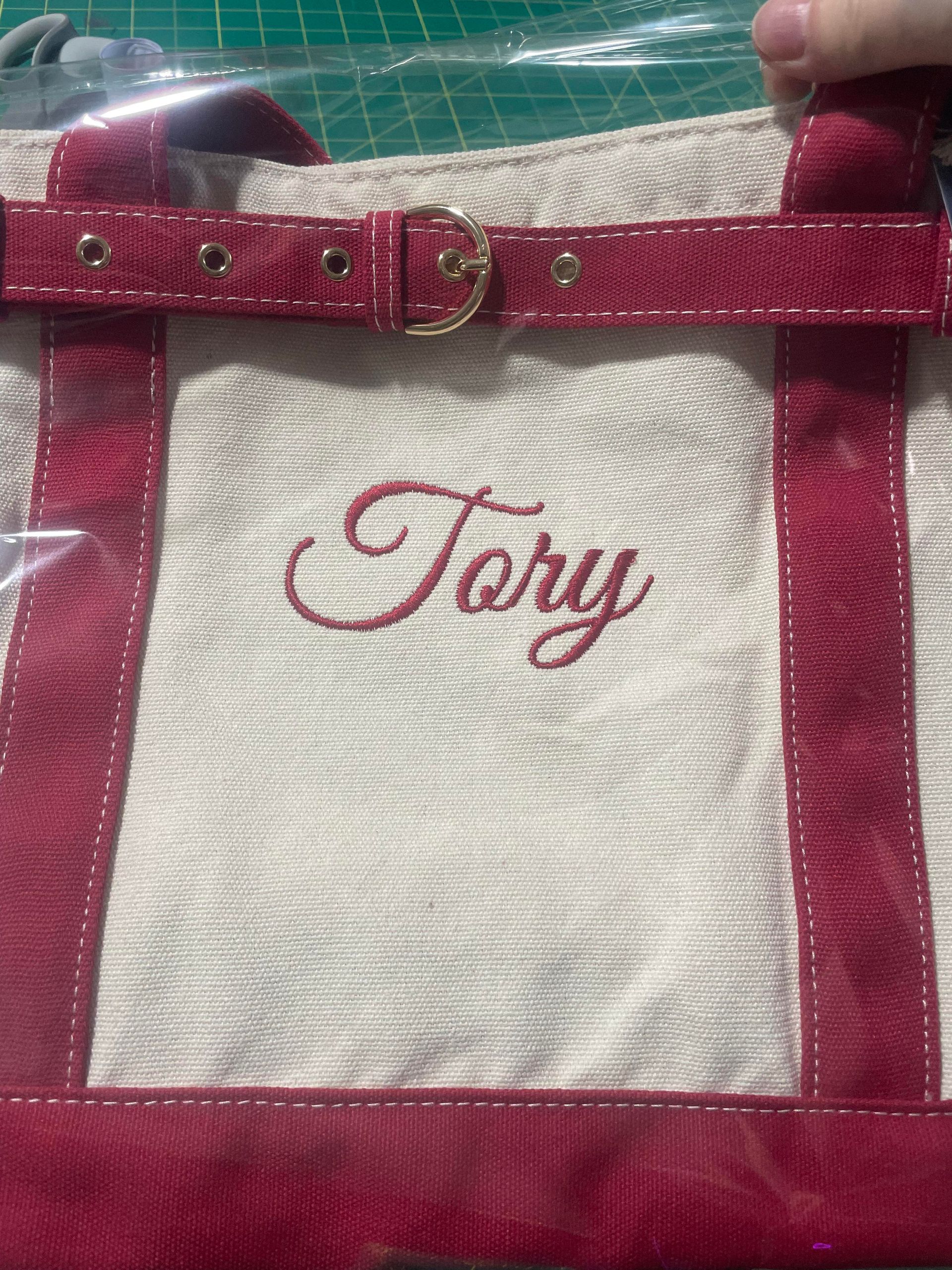 Pink and white tote bag with the name “Tory” embroidered on the front