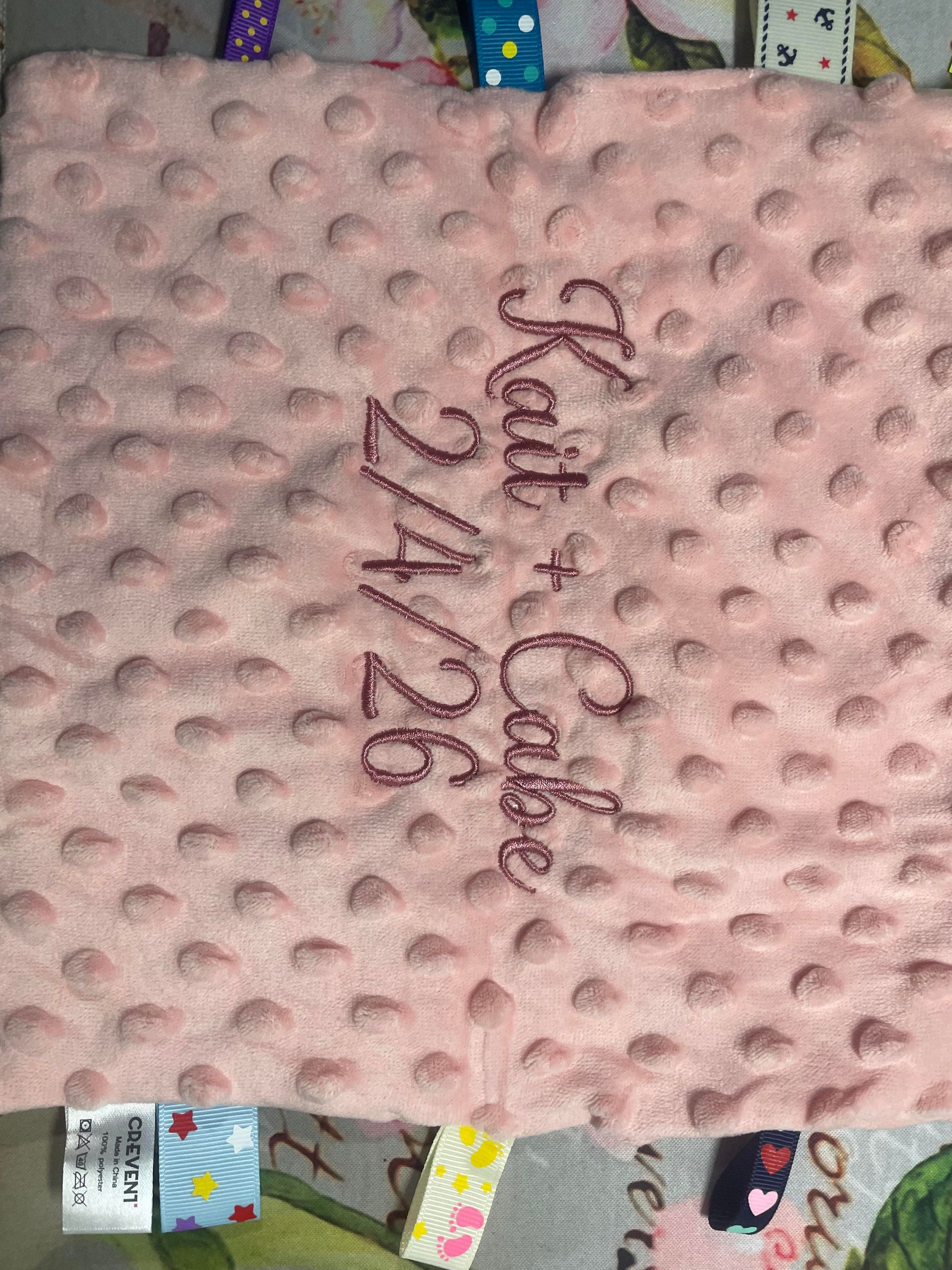 Pink textured blanket with embroidered “Kau & Caio 24/26” in the center.