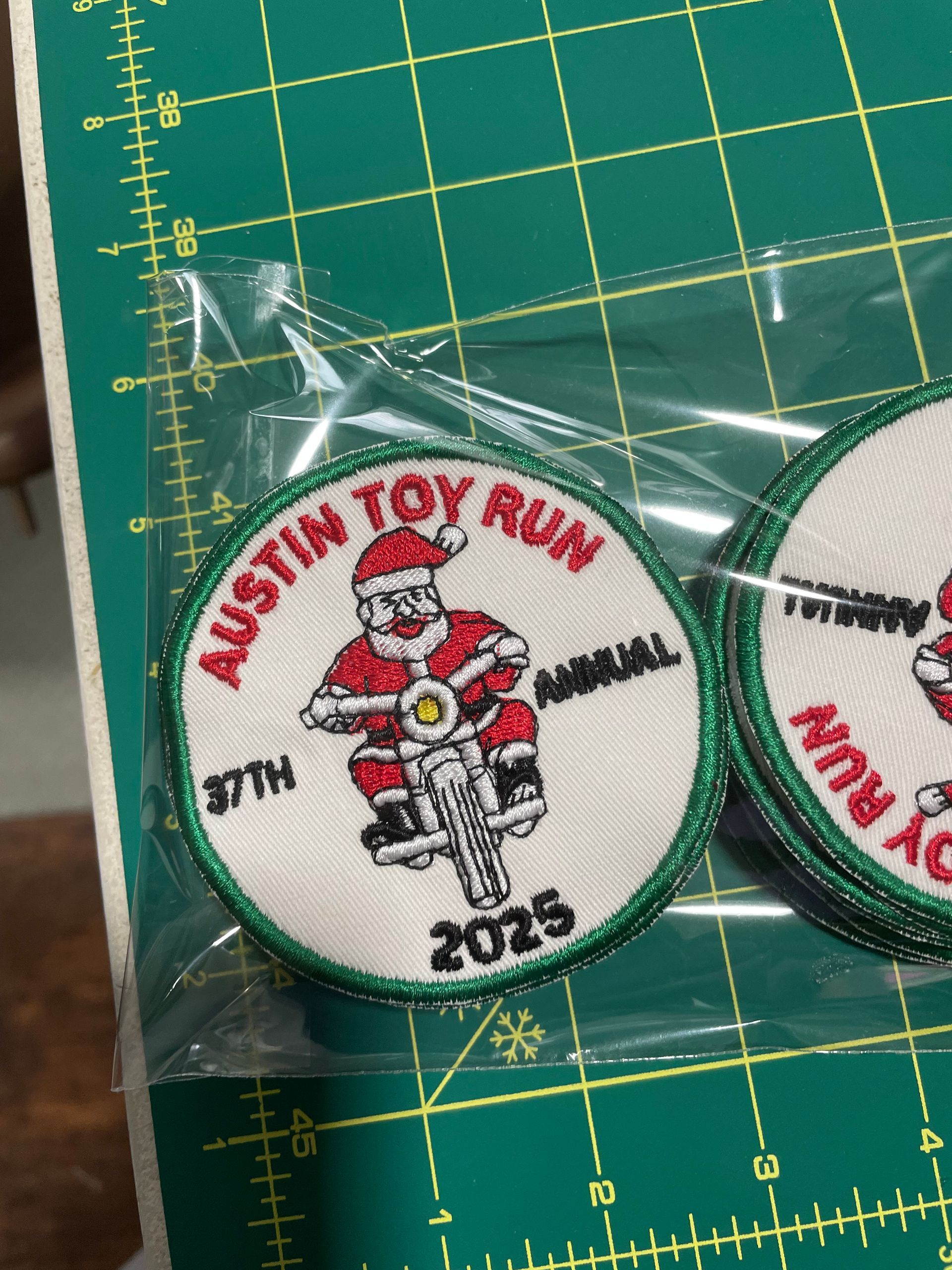 Austin Toy Run 30th anniversary biker patch in a clear plastic bag on a green cutting mat