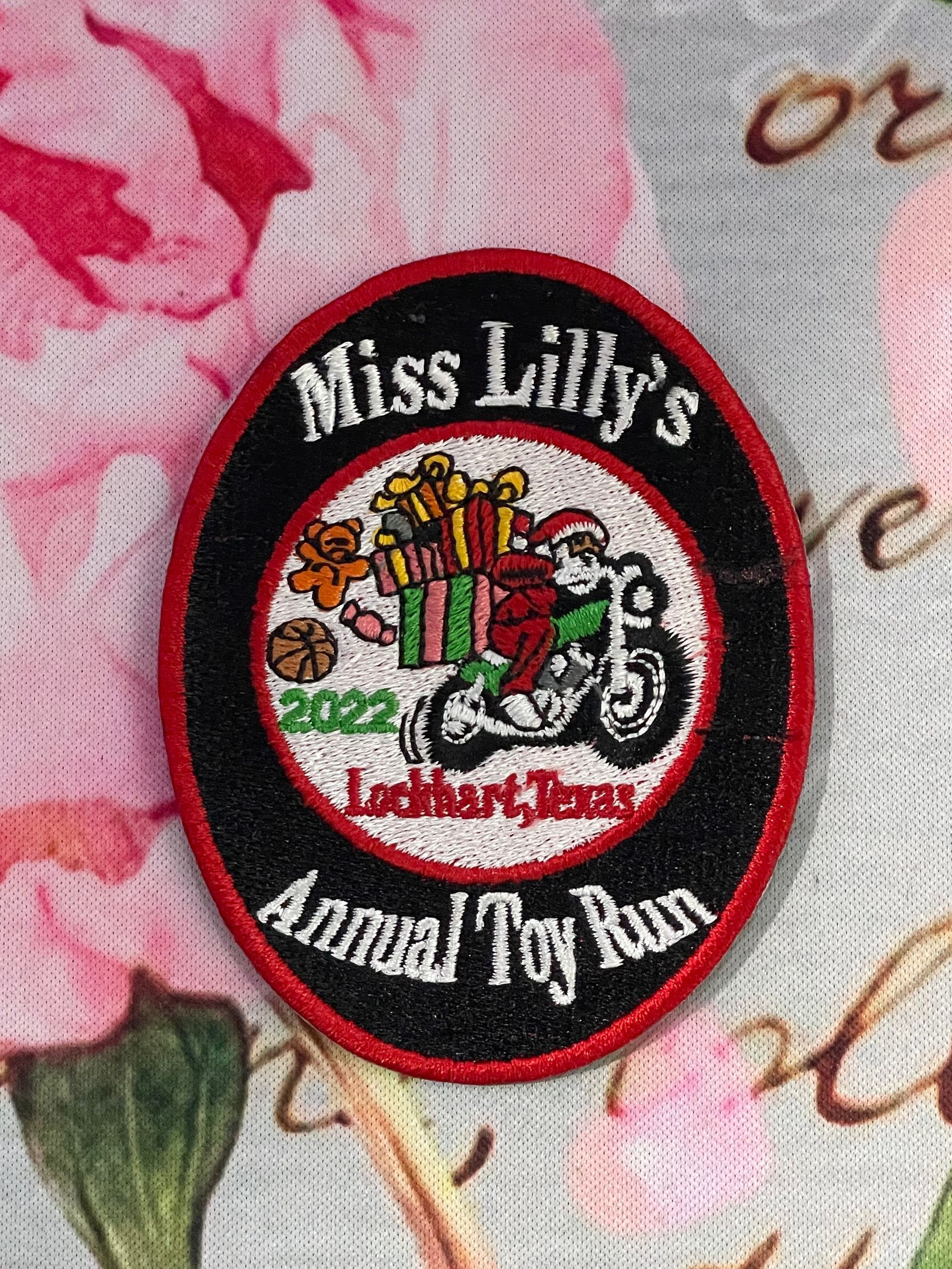 Miss Lilly’s Annual Toy Run patch with motorcycle and wrapped gifts on a floral fabric background
