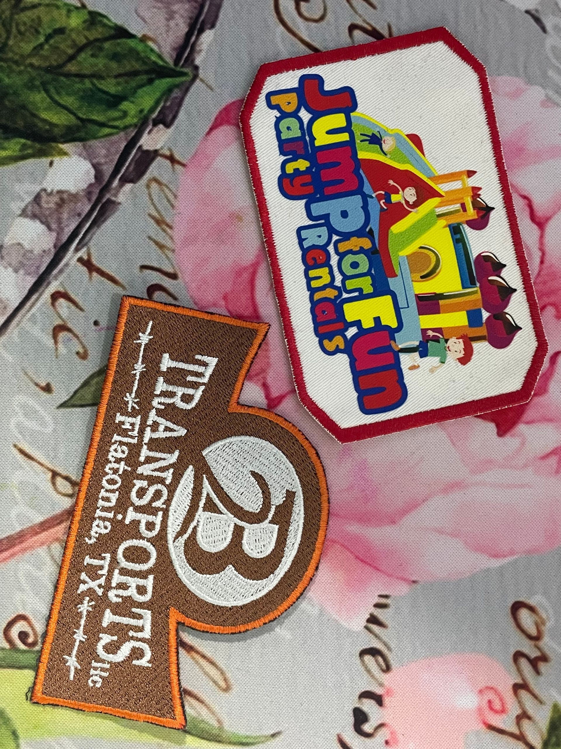 Two colorful logo patches on a floral fabric background: Jump for Joy and Transport Emotions.