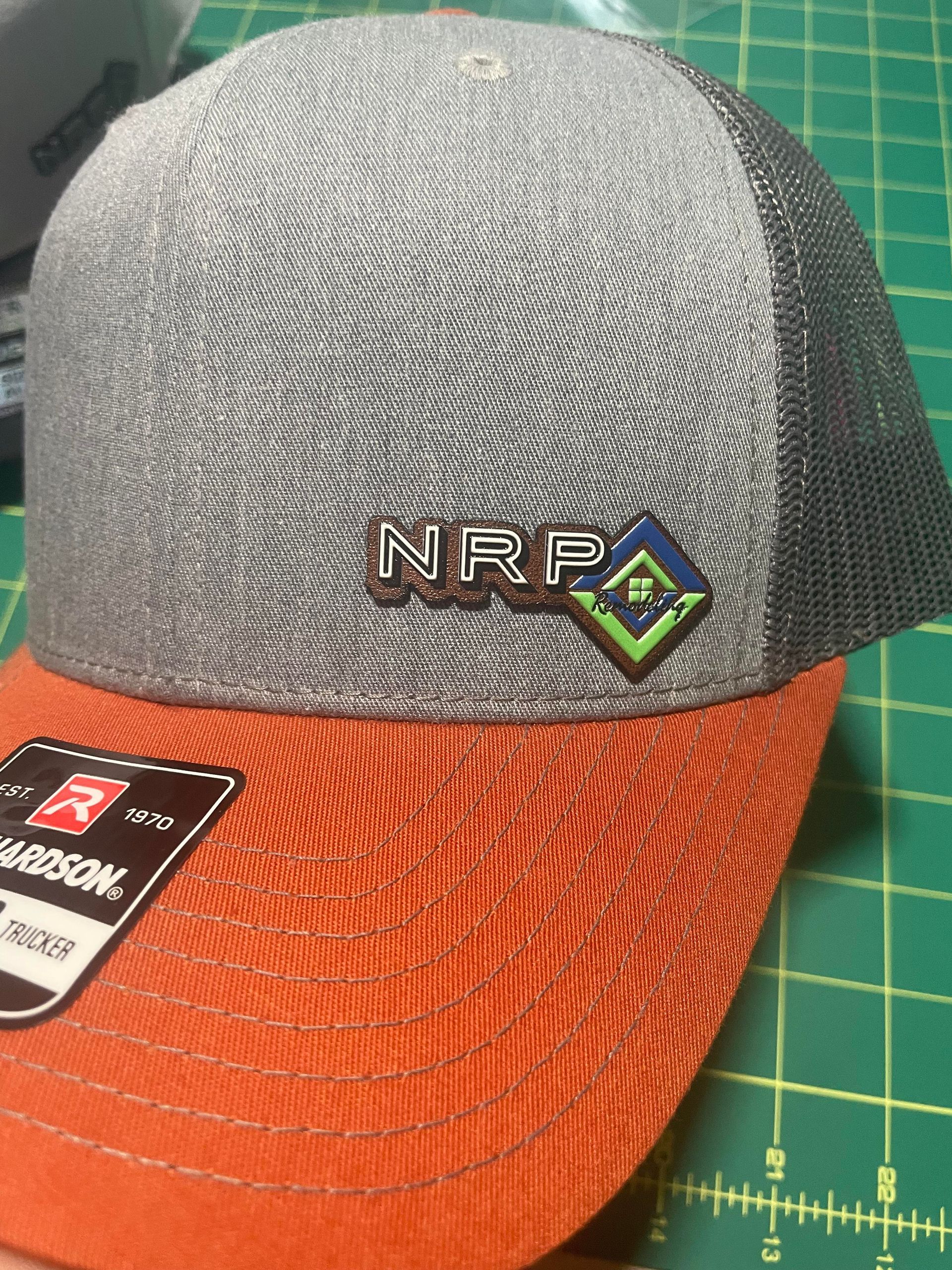 Gray and orange NRPA baseball cap on a cutting mat