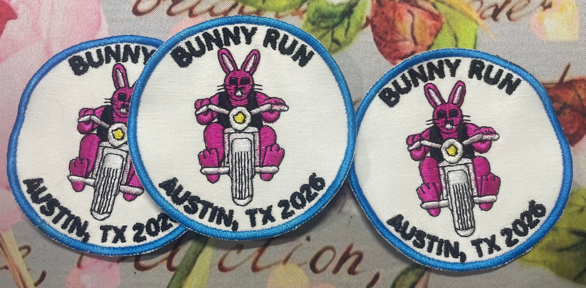 Three Bunny Run race medals with pink bunny designs and blue ribbons on a table