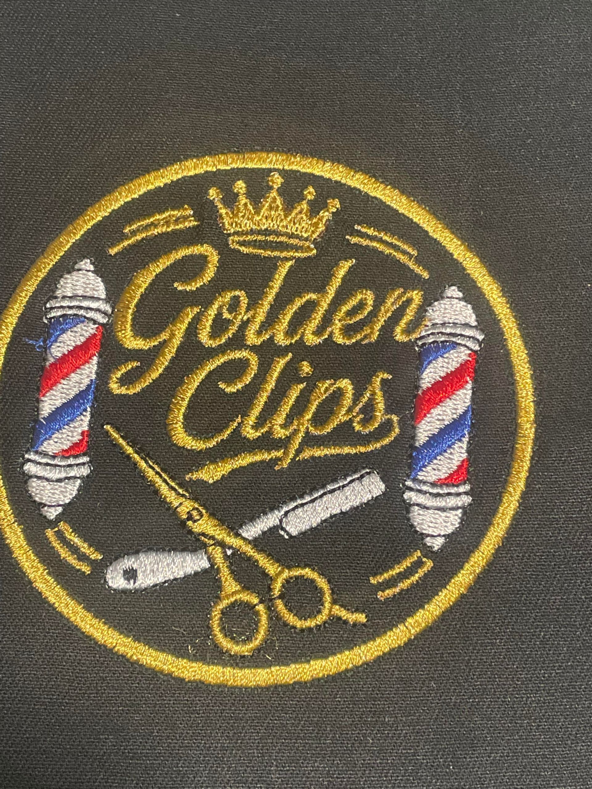 Golden Clips embroidery logo with gold scissors, crown, and red-white-blue barber poles on dark fabric