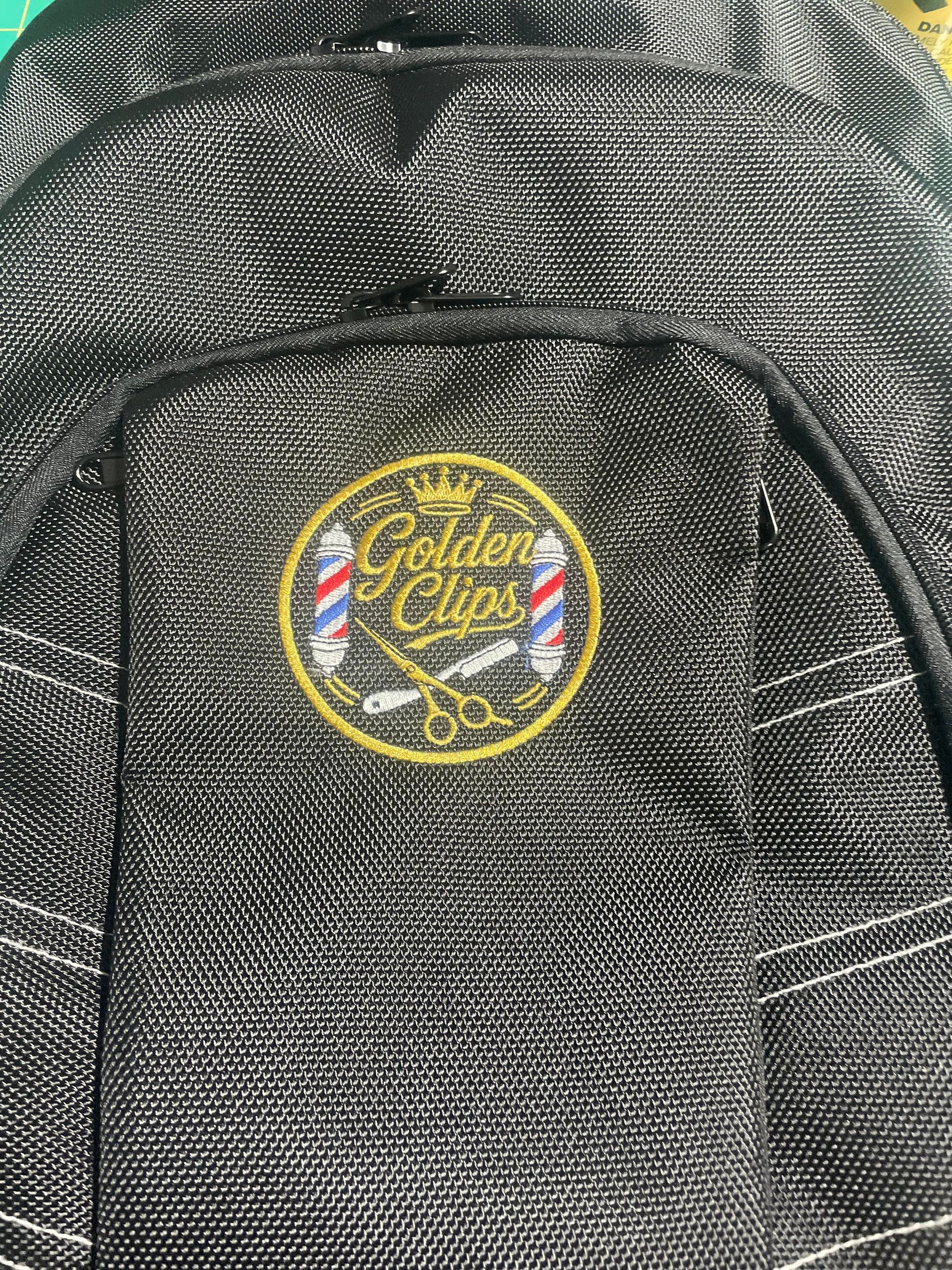 Close-up of a black mesh backpack with a yellow “Golden Class” circular logo.