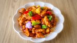 Sweet-and-sour chicken with colorful peppers and pineapple in a white bowl