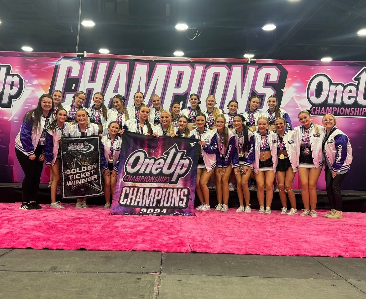 A group of cheerleaders are posing for a picture in front of a banner that says champions.
