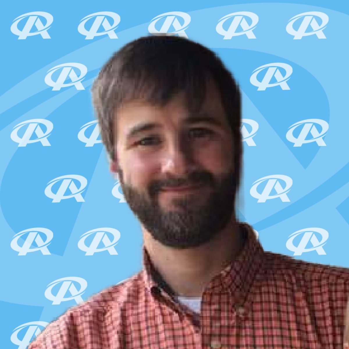 A man with a beard is wearing a plaid shirt