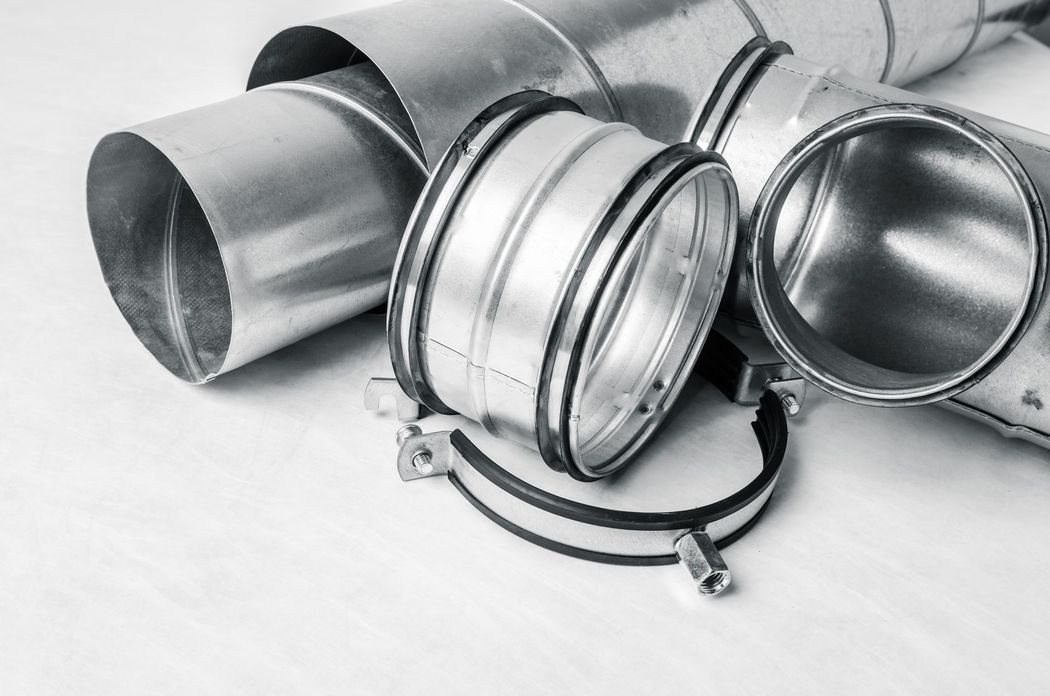 Raccordi e fascette per condotti di ventilazione argentati disposti su uno sfondo bianco