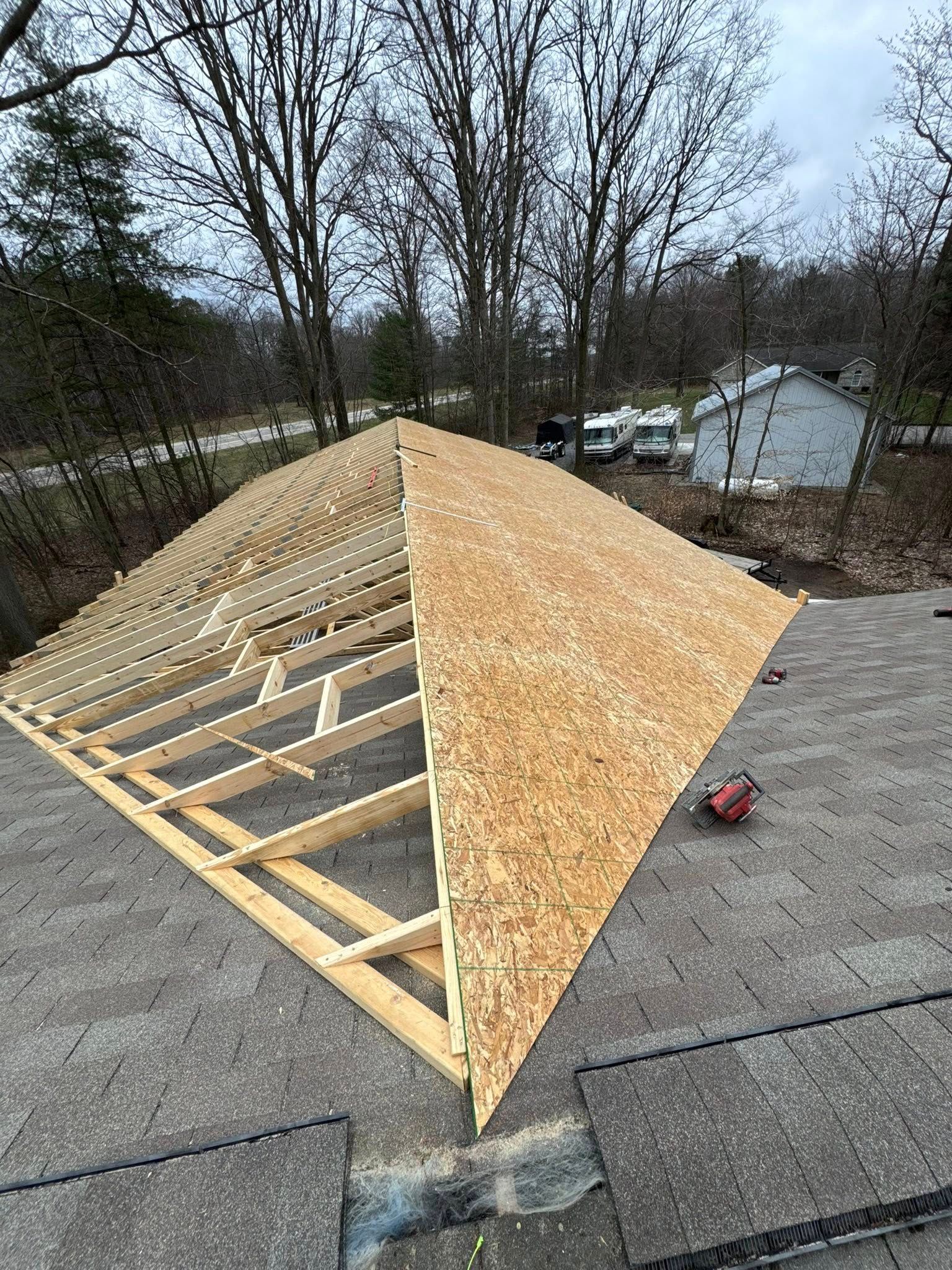 Roof under construction with plywood framing and OSB sheathing on a steep gable roof