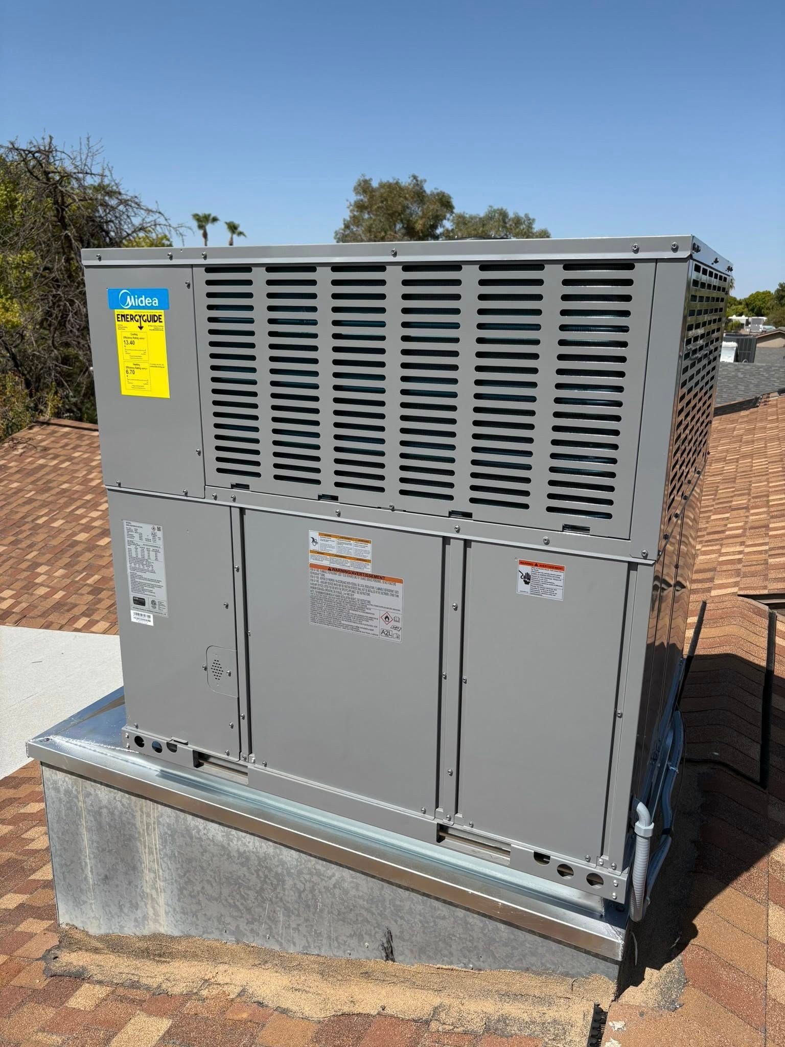 Gray electrical transformer unit outdoors on a concrete pad, with warning labels and vented panels.