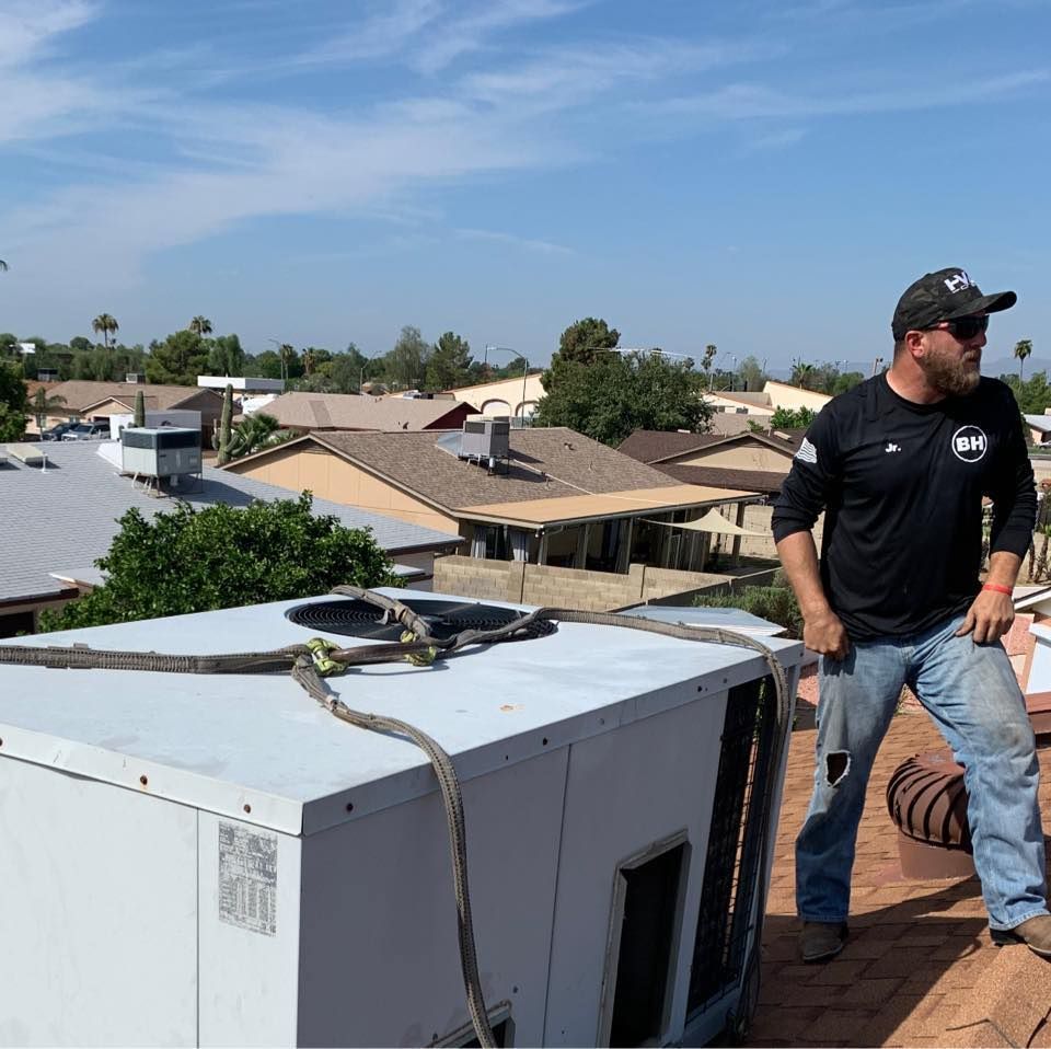 Technician standing on a rooftop beside a large HVAC unit under a clear blue sky