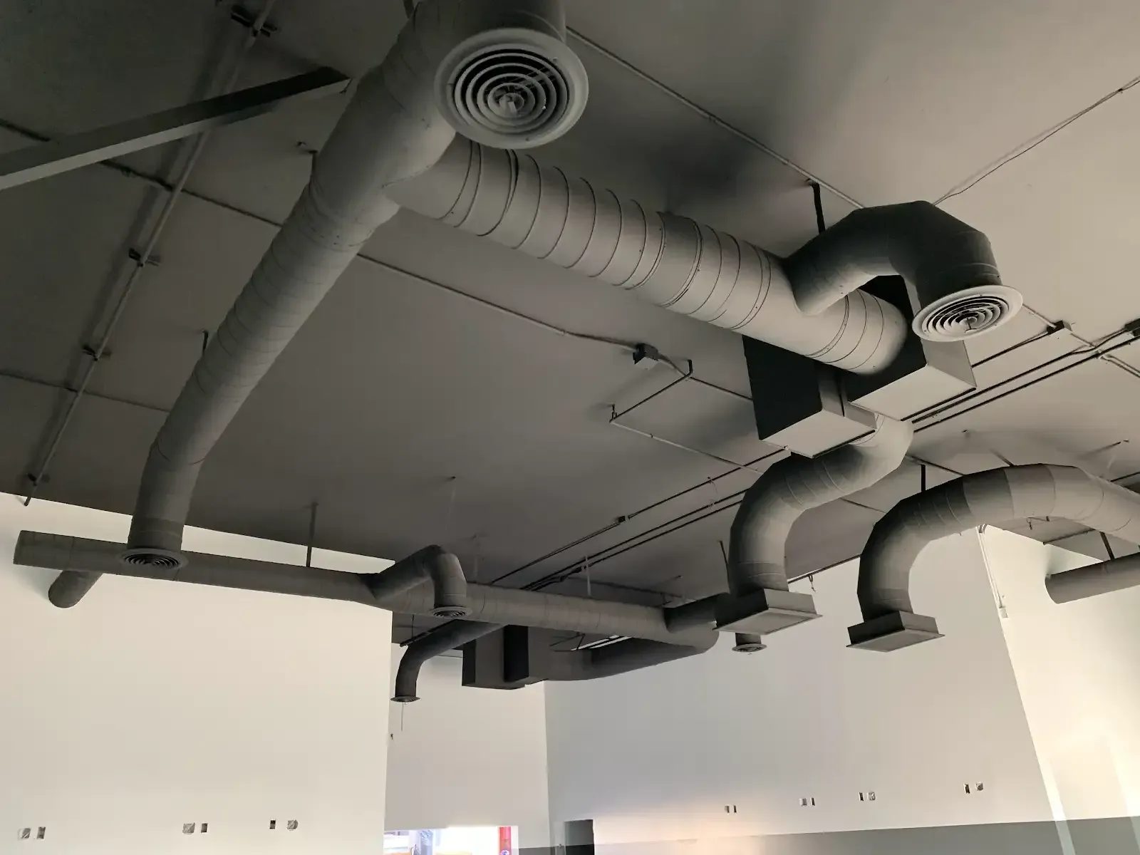 Ceiling with exposed gray HVAC ducts and vents in an industrial interior