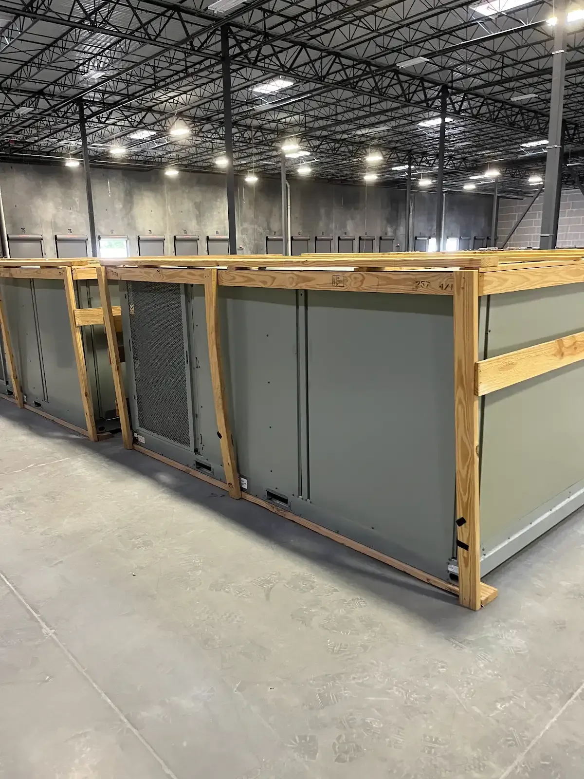 Large gray industrial crate with wooden framing in a warehouse with high ceiling and concrete floor