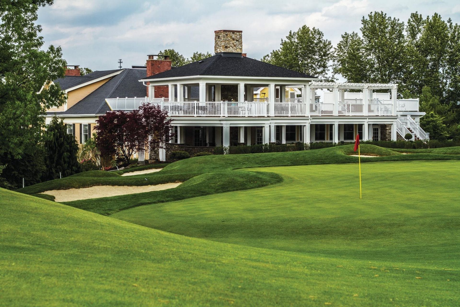 A large house is sitting on top of a lush green golf course.