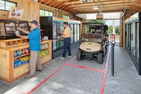 Two men are standing in a store next to a golf cart.