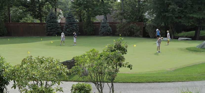 A group of people are playing golf on a green.