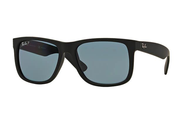 Un par de gafas de sol Ray-Ban con marco negro y lentes azules sobre fondo blanco.