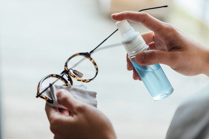 Una persona está limpiando un par de gafas con una botella de spray.