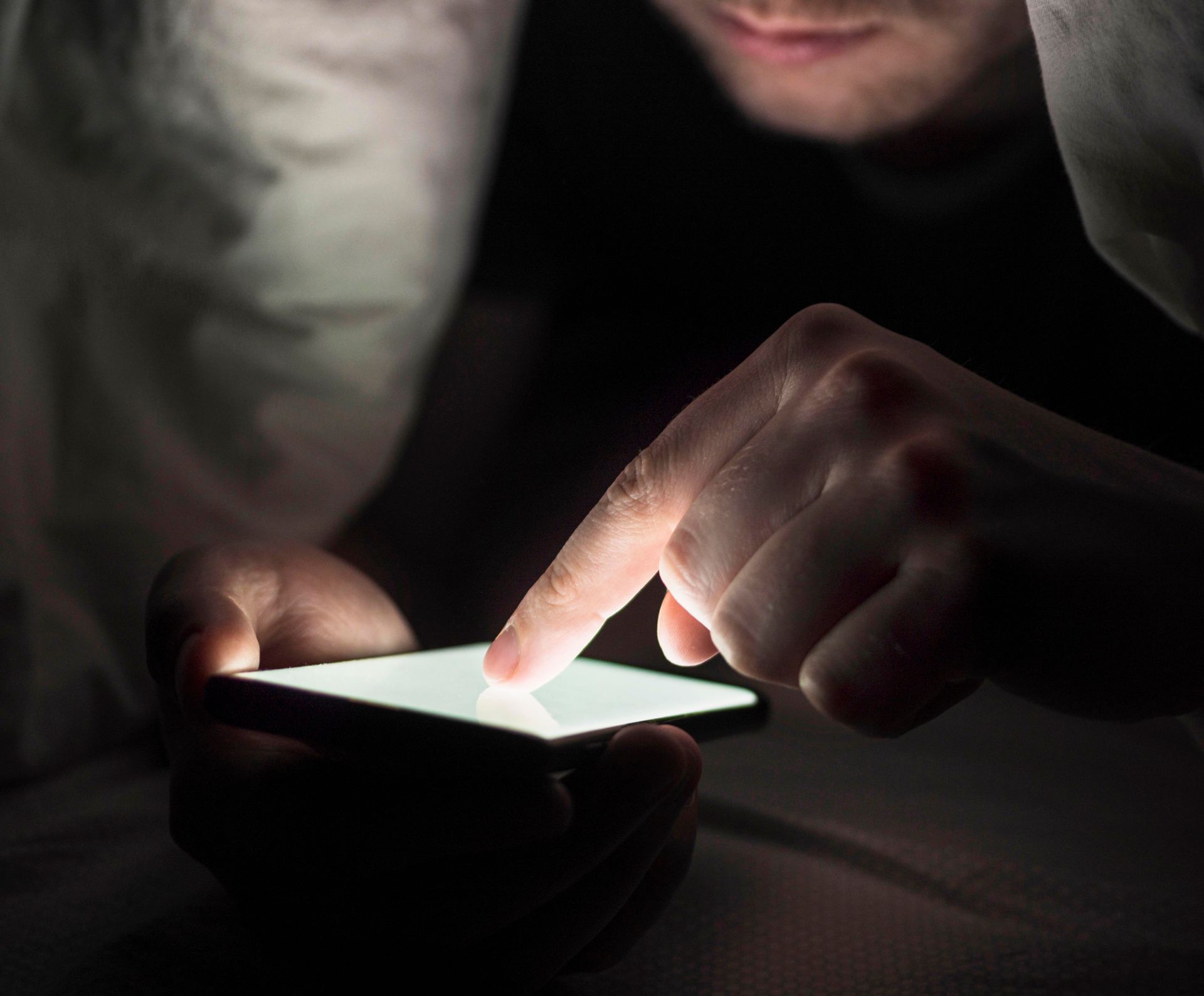 Una persona está usando un teléfono celular en la oscuridad.