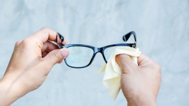 Una persona está limpiando sus gafas con un paño.