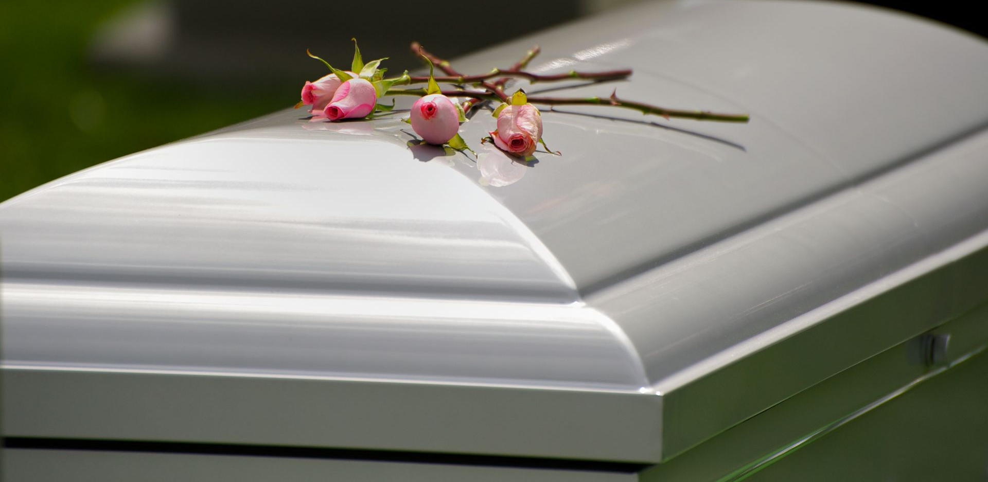 White coffin with pink flowers on top