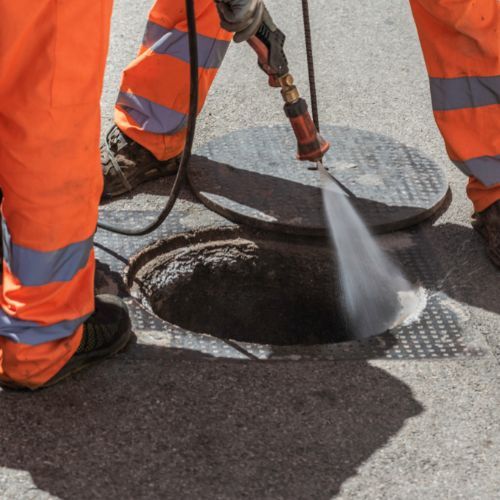 A Manhole Cover is Being Cleaned With a Hose