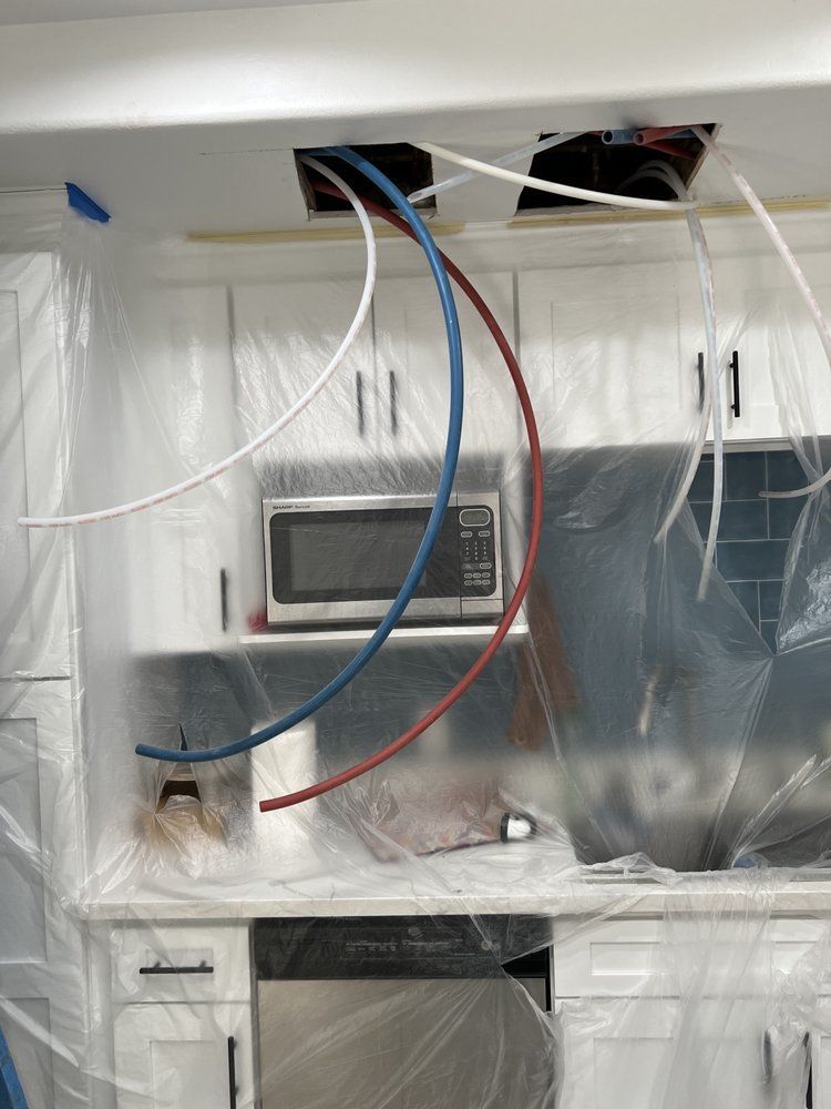 A Kitchen is Covered in Plastic and Has Wires Coming Out of the Ceiling