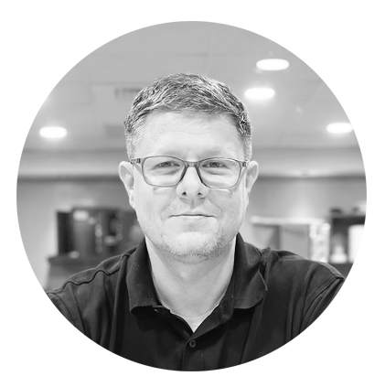 A black and white photo of a man wearing glasses and a black shirt.