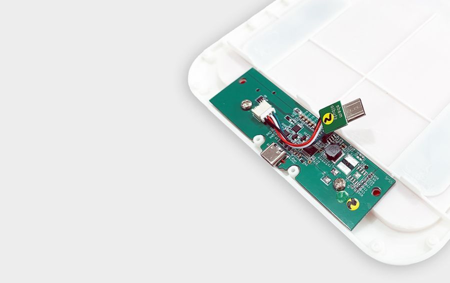 Green circuit board with ports and components inside a white plastic enclosure.