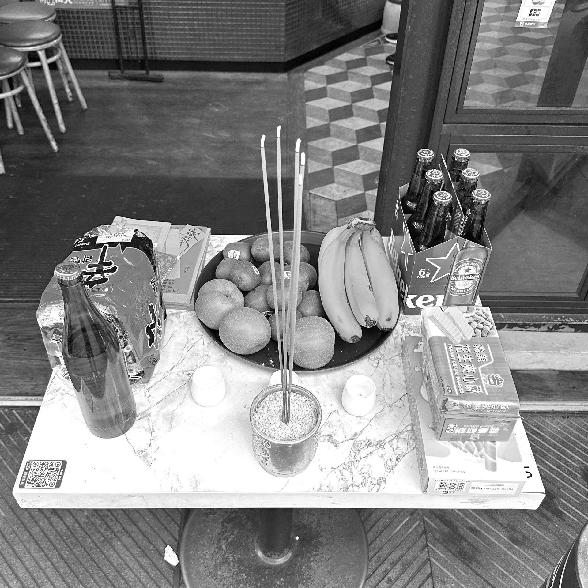 A table with a bowl of fruit and incense sticks on it.