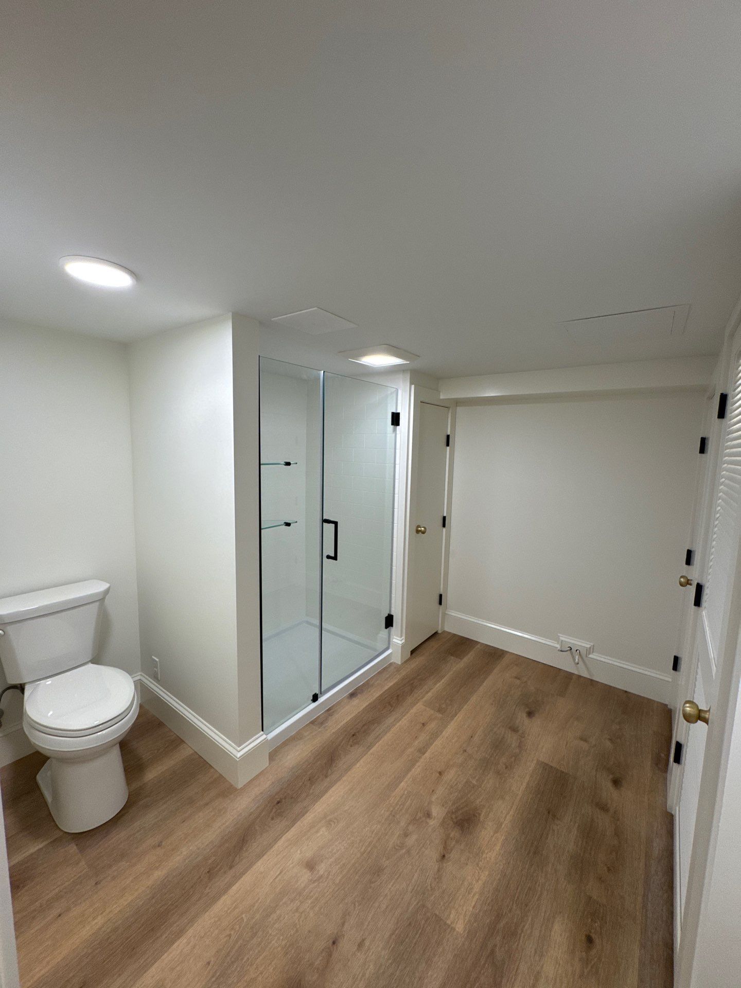 Bright white bathroom with black-and-white tile floor, sink, toilet, window, and hanging plants