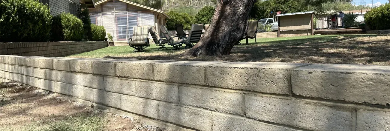 Retaining wall installation supporting soil and defining a landscaped area