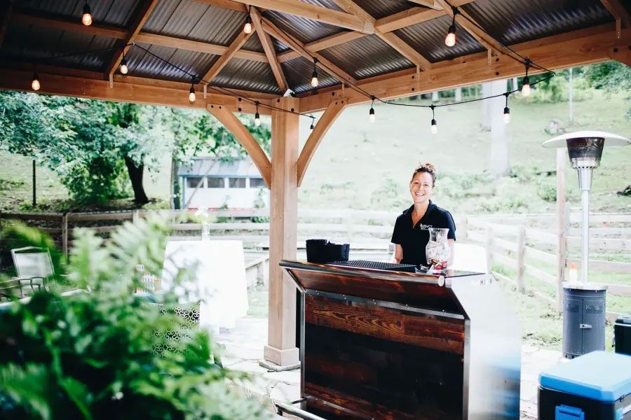 A woman is standing behind a bar under a gazebo.