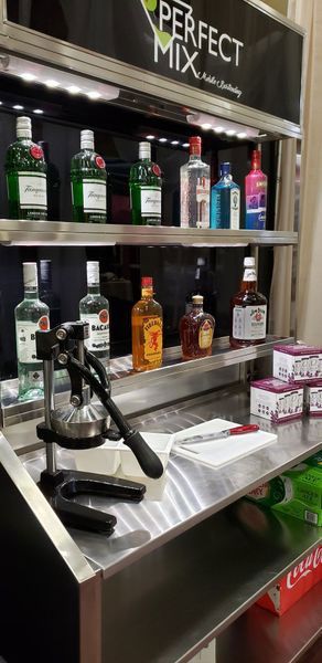 A stainless steel counter with bottles of alcohol on it.