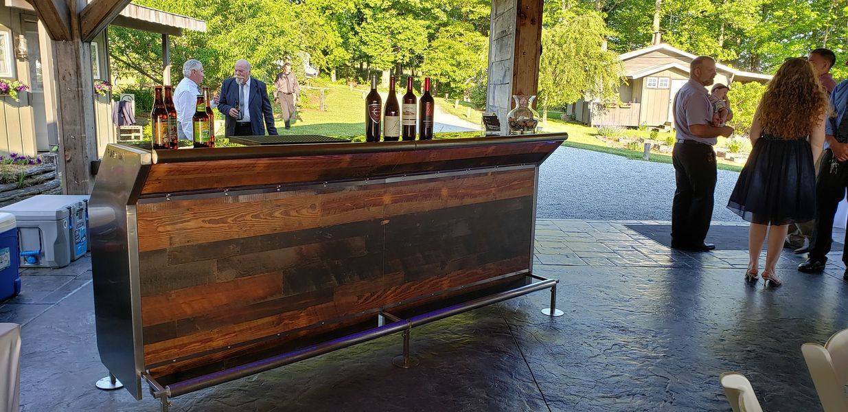 A group of people are standing around a wooden bar.