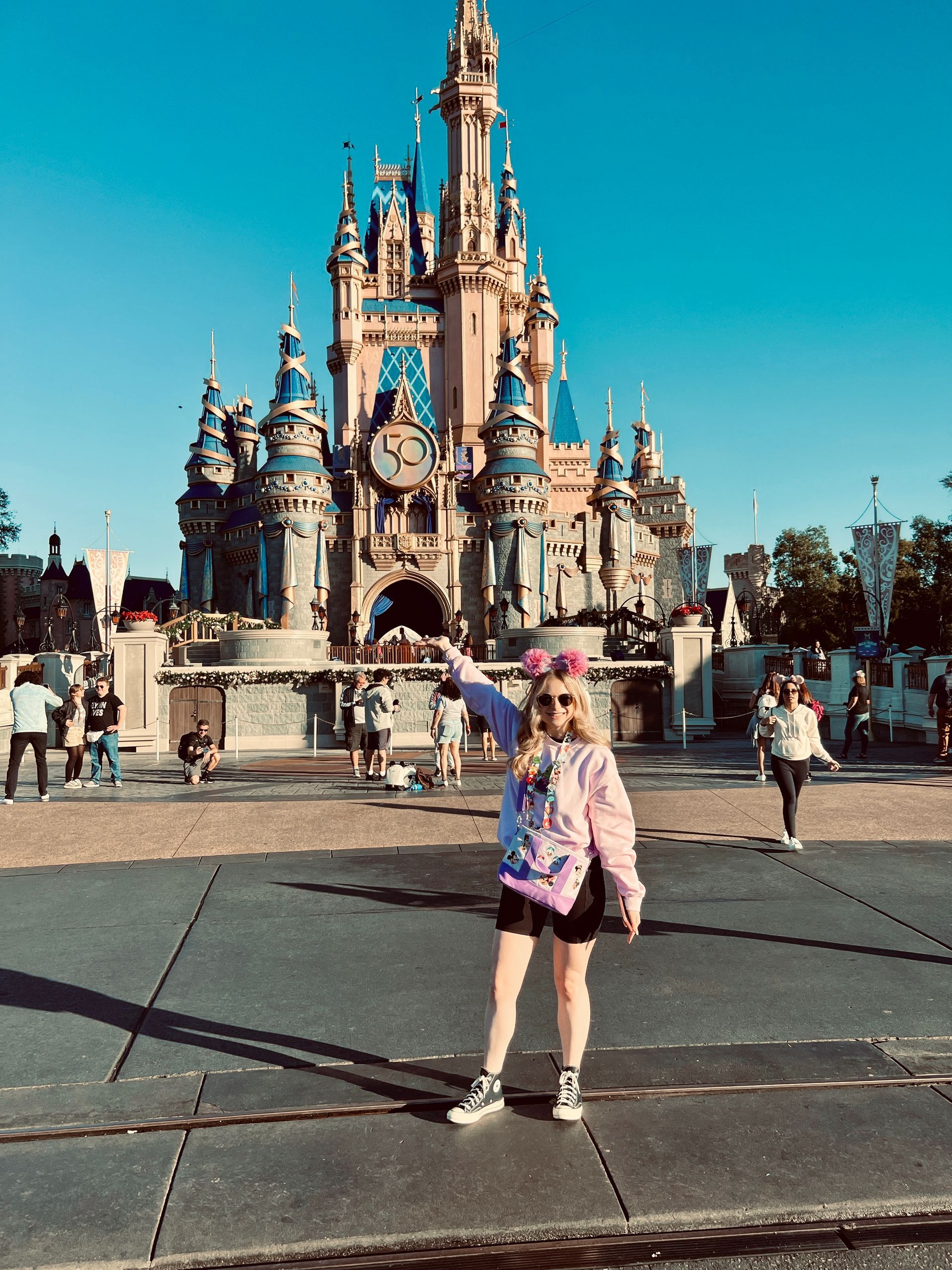 Woman points towards Cinderella's castle at Disney World. Blue sky, sunny day.