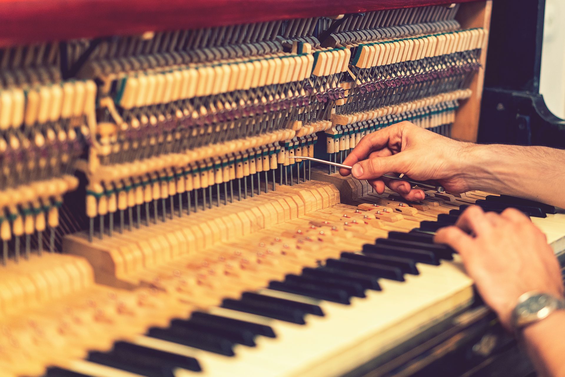 A person is tuning a piano with a tuning tool.