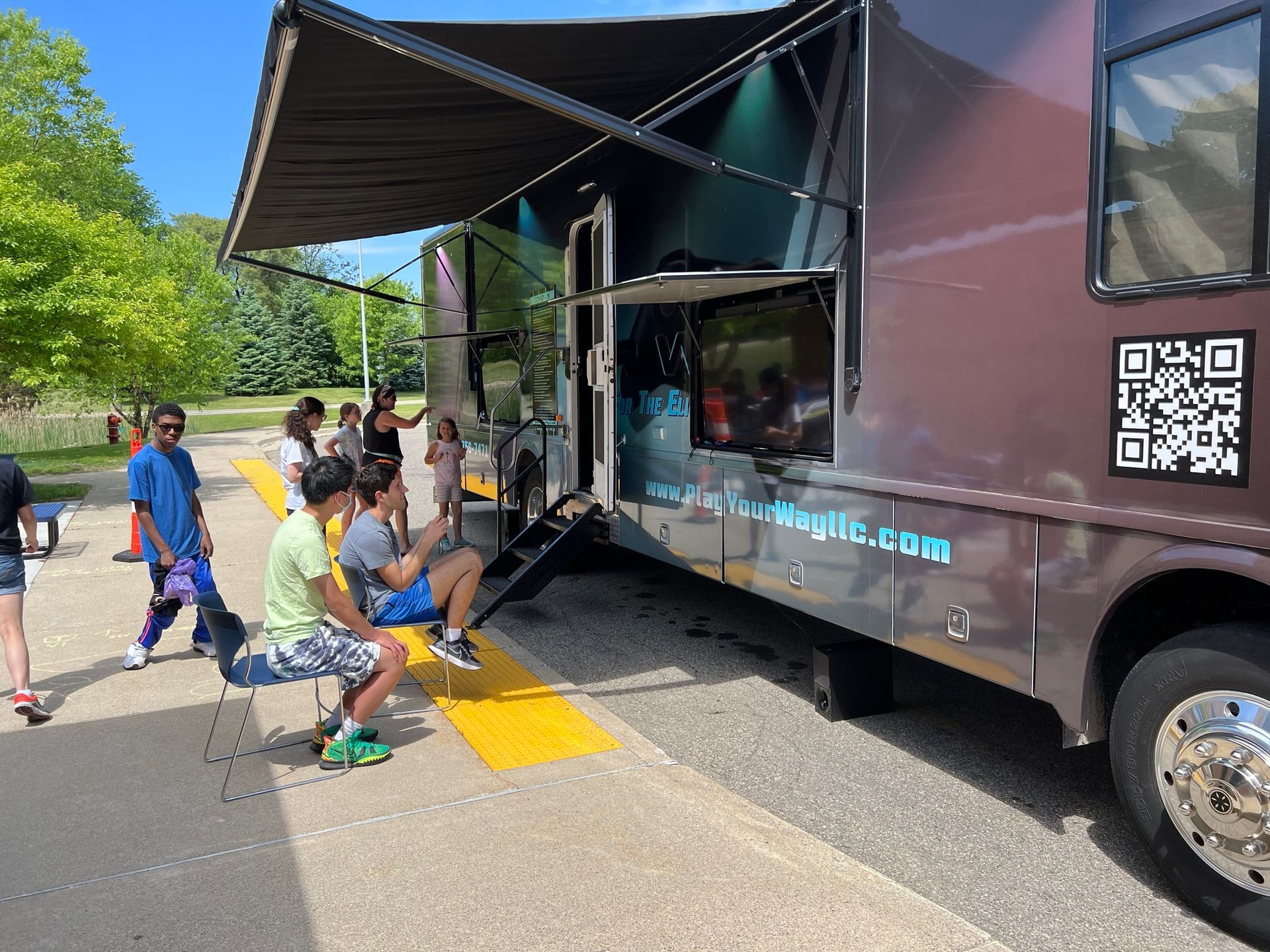children playing in front of a play your way bus