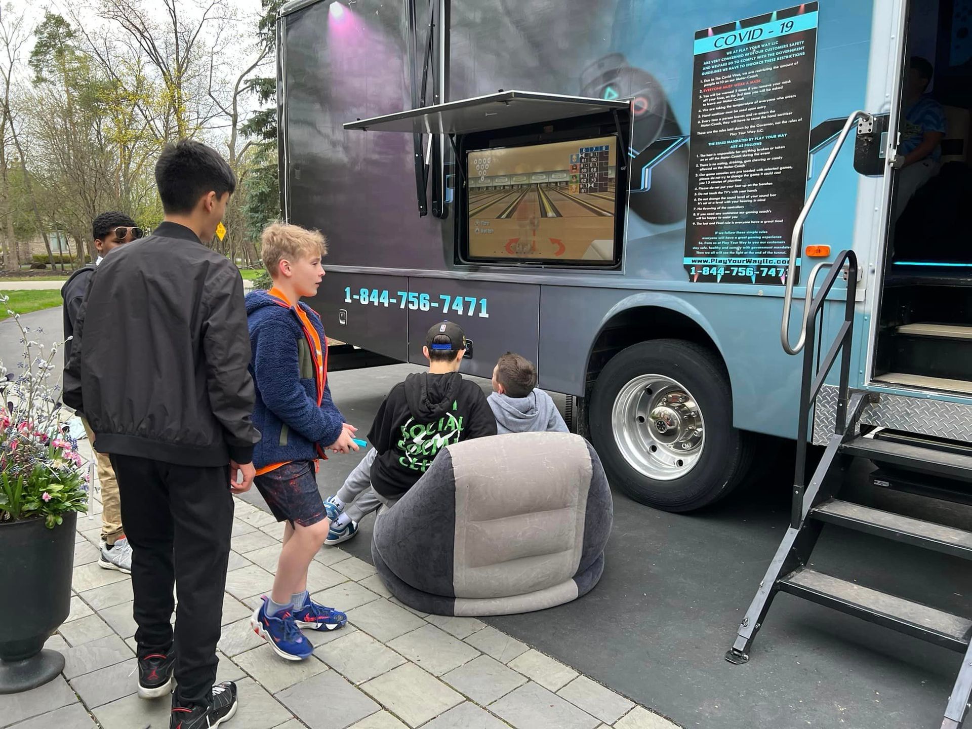 a group of children are sitting in front of a video game truck