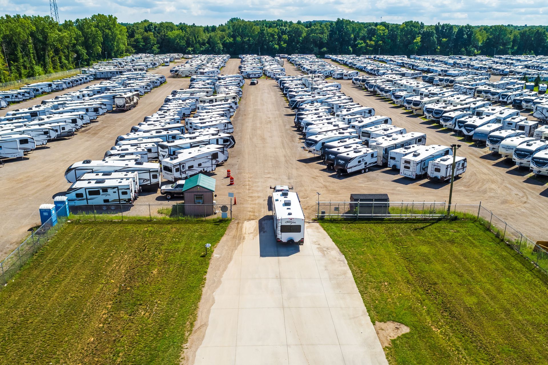 An aerial view of a crowded storage lot filled with rows of white recreational vehicles on a sunny day.