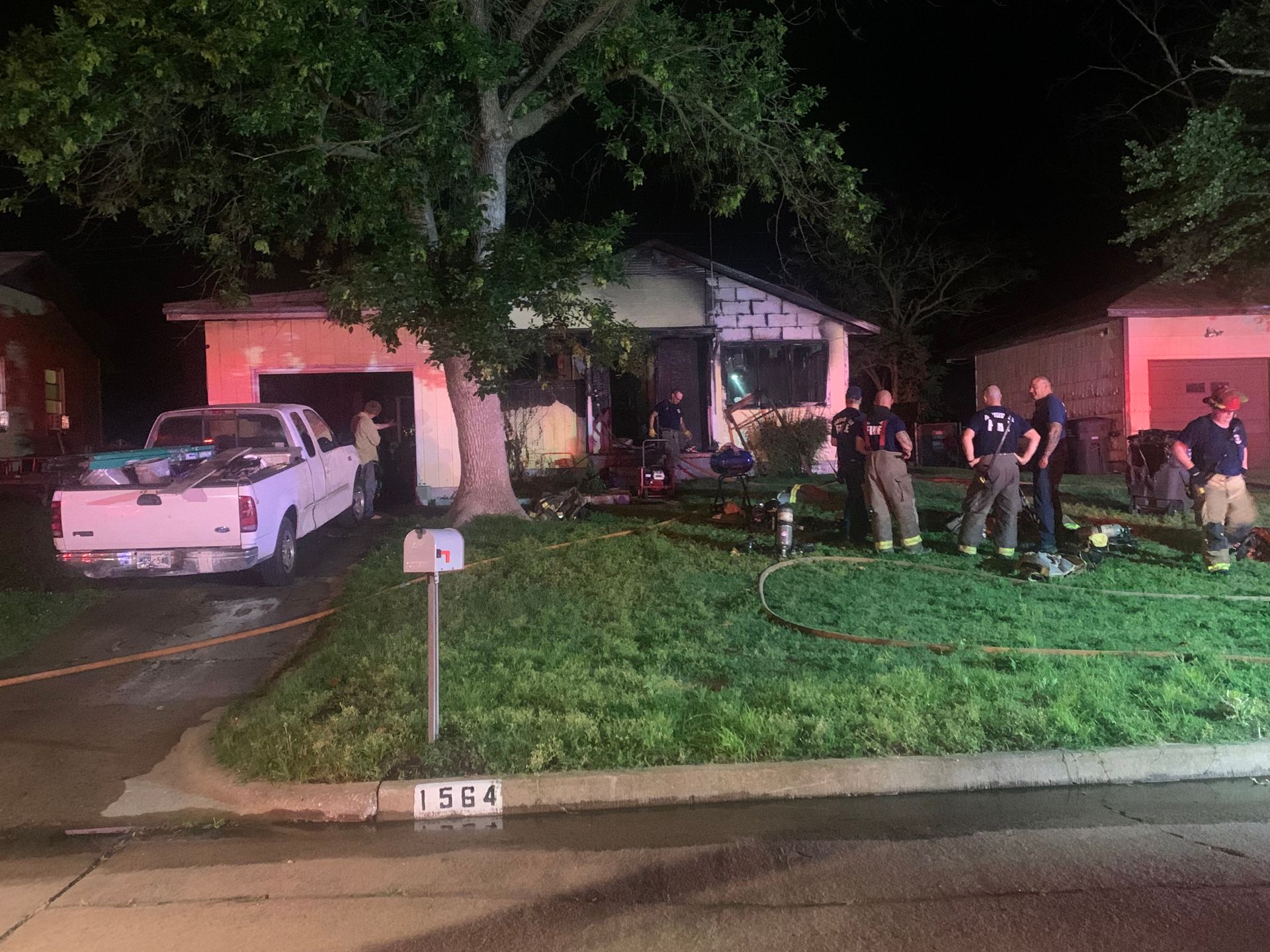 A group of firefighters are standing in front of a house.