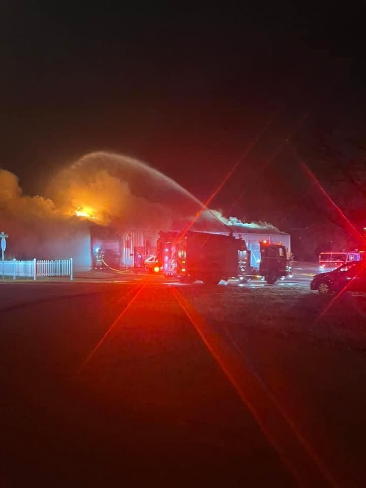 A fire truck is spraying water on a fire at night.
