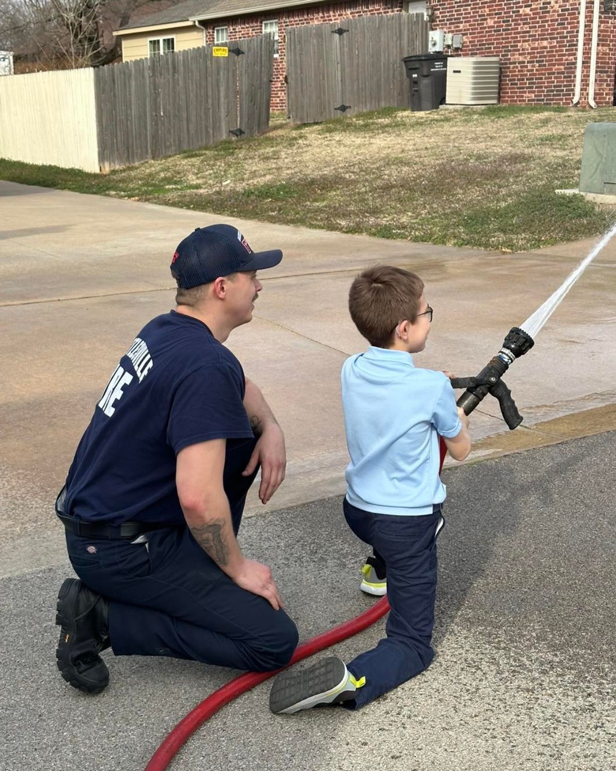 A man and a boy are playing with a fire hose.