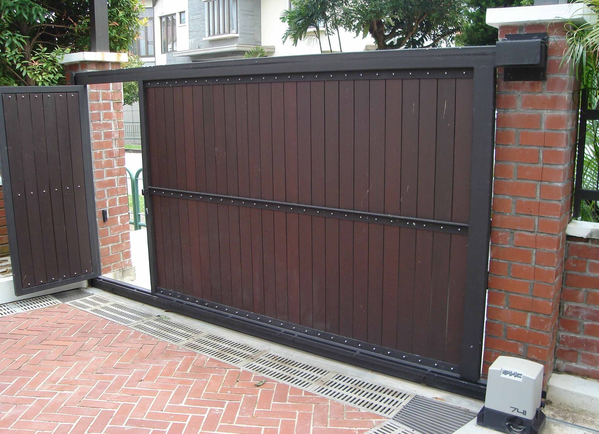A wooden sliding gate with a brick wall behind it